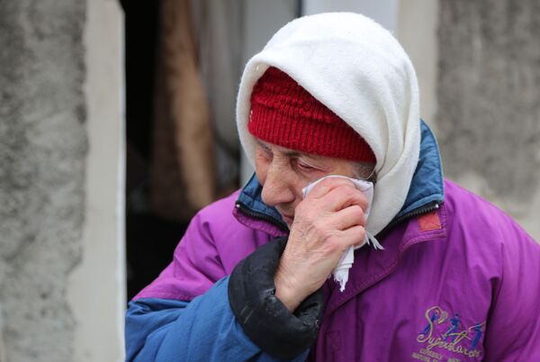 Пожилая женщина плачет около жилого дома в Киевском районе Донецка, разрушенном в результате обстрела - Sputnik Кыргызстан