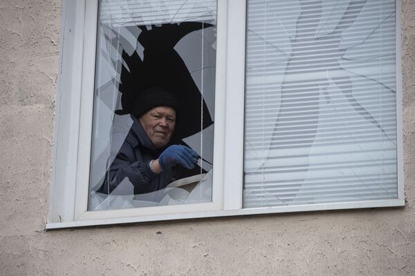Мужчина достает осколки из разбитой рамы в жилом доме в городе Счастье  - Sputnik Кыргызстан