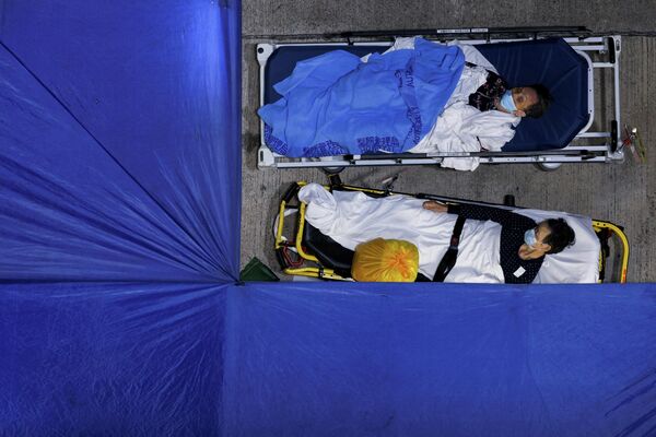 Пациенты спят в импровизированной зоне лечения от COVID-19 возле больницы в Гонконге. Ранее сообщалось, что Гонконг обновил рекорд по ежедневному приросту заболеваемости. За сутки здесь зафиксировали больше 10 тысяч случаев инфицирования. - Sputnik Кыргызстан
