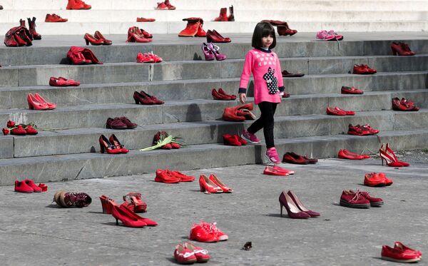 Девочка посреди инсталляции в честь 8 Марта, выполненной из женских красных туфель, как символ осуждения насилия в отношении женщин в Тиране (Албания) - Sputnik Кыргызстан
