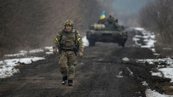 Украинский военнослужащий на фоне танка в Сумской области (Украина) - Sputnik Кыргызстан