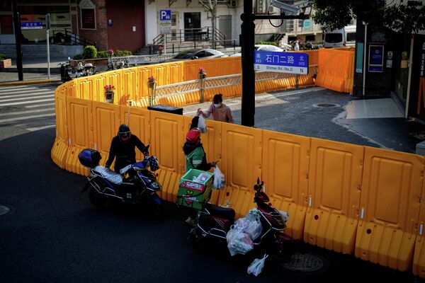 Работник службы доставки передает женщине еду через ограждение закрытой зоны в Шанхае (Китай) из-за новой вспышки COVID-19 - Sputnik Кыргызстан
