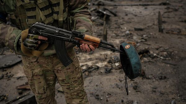 Украинский военнослужащий с беретом на оружии в аэропорту в Гостомеле (Украина) - Sputnik Кыргызстан