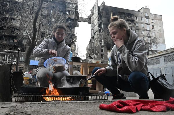 Жители Мариуполя готовят еду во дворе разрушенного дома - Sputnik Кыргызстан