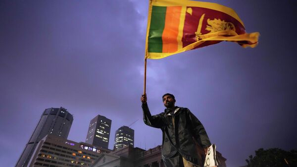 Мужчина держит национальный флаг во время антиправительственных акций протеста в Коломбо, Шри-Ланка - Sputnik Кыргызстан