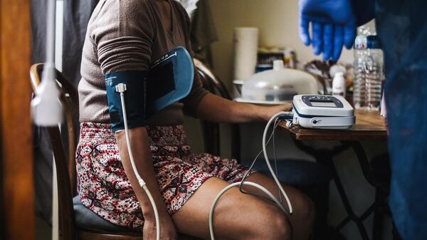 Работник скорой помощи проверяет артериальное давление женщины. Архивное фото - Sputnik Кыргызстан