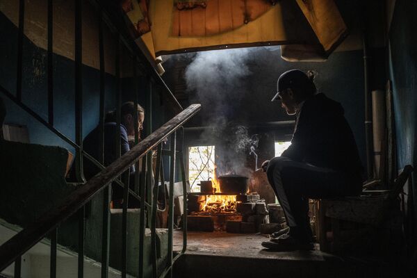 Местные жители готовят еду на лестничном пролете в подъезде своего дома в Мариуполе - Sputnik Кыргызстан