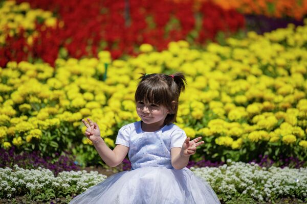 Девочка позирует на фоне цветов. - Sputnik Кыргызстан
