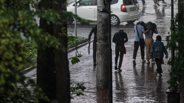 Люди идут по улице в Бишкеке во время сильного дождя. Архивное фото - Sputnik Кыргызстан