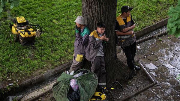 Сотрудники муниципальной службы под деревом во время дождя в Бишкеке. Архивное фото - Sputnik Кыргызстан