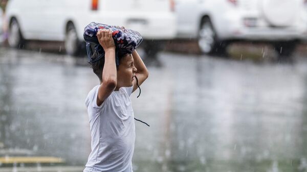 Мальчик укрывается от дождя в Бишкеке. Архивное фото - Sputnik Кыргызстан