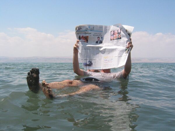 Человек читает газету на поверхности Мертвого моря — самого соленого водоема на Земле - Sputnik Кыргызстан