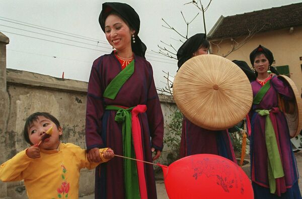 Девочка ест фруктовый лед рядом с исполнителями куан хо в традиционных костюмах в северной провинции Бакнинь (Вьетнам) - Sputnik Кыргызстан