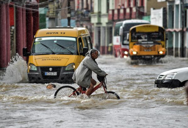Мужчина едет на велосипеде по затопленной улице в Гаване (Куба). Наводнения, вызванные проливными дождями, унесли жизни по меньшей мере трех человек. - Sputnik Кыргызстан
