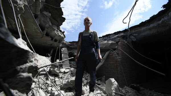 Мужчина на месте попадания снаряда ВСУ в крышу центра охраны материнства в Донецке - Sputnik Кыргызстан