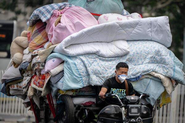 Мотоциклист в Пекине (Китай) везет тележку, нагруженную постельными принадлежностями - Sputnik Кыргызстан