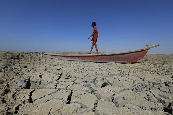 Мальчик ходит по лодке на дне высохшего болота в Ираке. Из-за отсутствия дождей уровень воды в реках Тигр и Евфрат упал до 60 процентов, что привело к сильным засухам в стране. - Sputnik Кыргызстан
