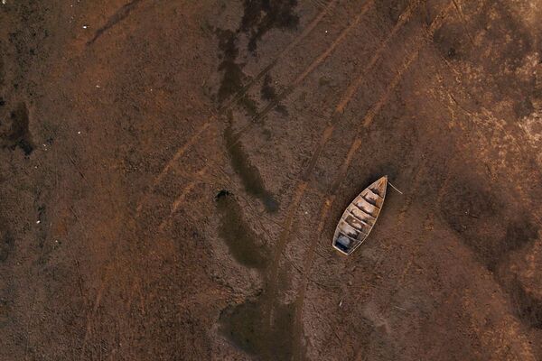 Следы от автомобиля на дне реки возле севшей на мель лодки на реке Парана (Аргентина). Уровень воды в ней достиг исторического минимума. - Sputnik Кыргызстан