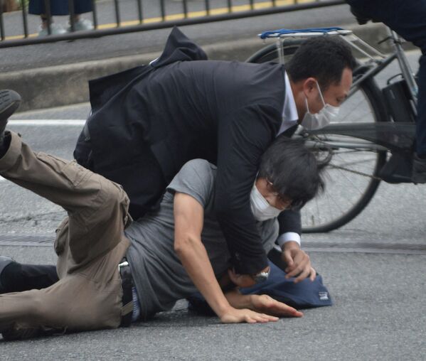 Подозреваемый в убийстве бывшего премьер-министра Японии Синдзо Абэ повален на землю полицией. Абэ был убит в городе Нара во время уличного выступления. - Sputnik Кыргызстан