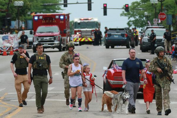 Полицейские сопровождают семью с места стрельбы на параде по случаю Дня независимости США в Хайленд-Парке (штат Иллинойс). В результате стрельбы шесть человек были убиты и 19 ранены. - Sputnik Кыргызстан