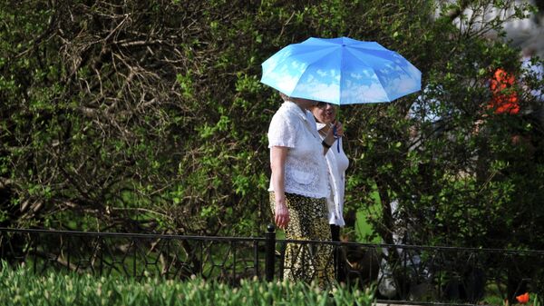 Люди гуляют в парке укрываясь зонтом от солнца. Архивное фото - Sputnik Кыргызстан