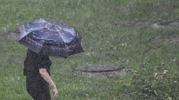 Женщина идет по улице во время сильного дождя. Архивное фото - Sputnik Кыргызстан