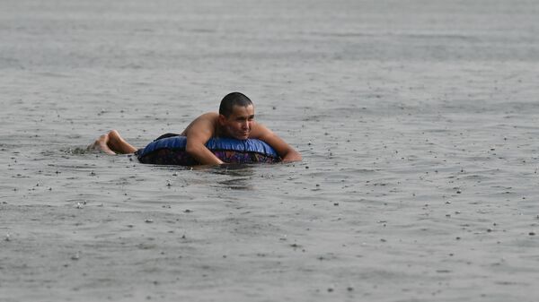 Мужчина плавает в озере с надувным кругом во время дождя. Архивное фото - Sputnik Кыргызстан