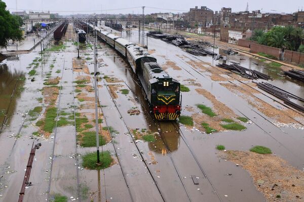 Поезд движется по затопленным железнодорожным путям после сильных муссонных дождей в Хайдарабаде (Индия) - Sputnik Кыргызстан