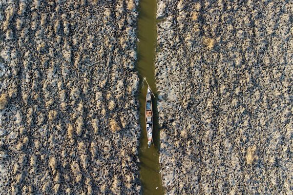 Вид с воздуха на рыбацкую лодку, плывущую по каналу в отступающих южных болотах Ирака - Sputnik Кыргызстан