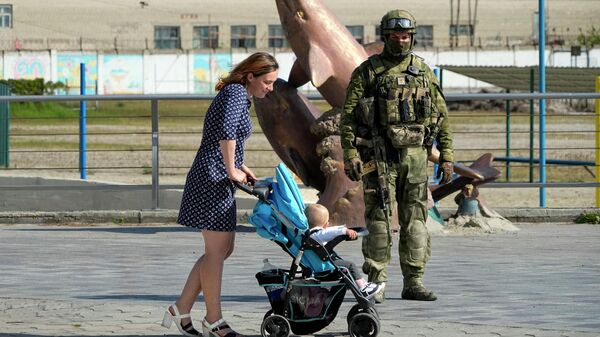 Женщина с ребенком проходит мимо российского солдата в Херсоне. Архивное фото - Sputnik Кыргызстан