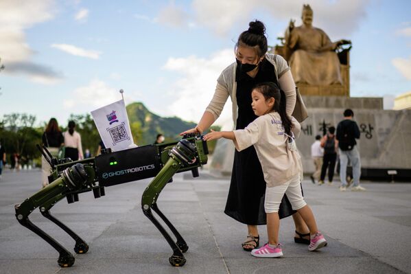 На фото: женщина с дочерью дотрагиваются до &quot;собаки-робота&quot; на площади в Сеуле - Sputnik Кыргызстан
