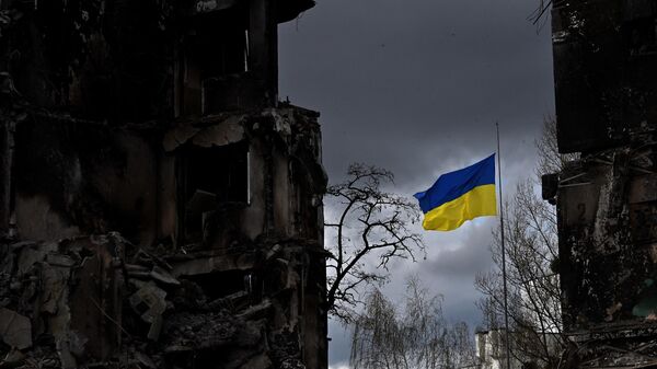 Украинский флаг между разрушенными во время бомбардировки зданиями в Киевской области. Архивное фото - Sputnik Кыргызстан