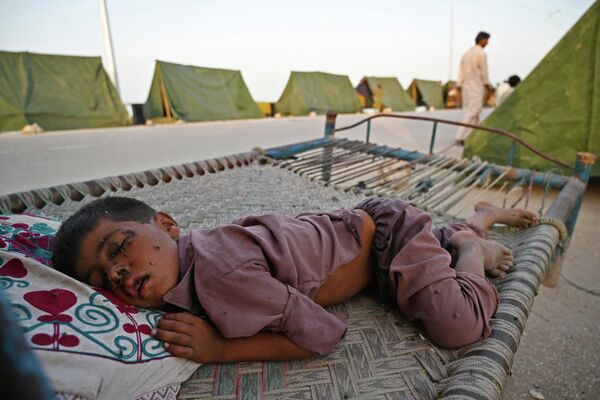 Пострадавший от страшного наводнения мальчик спит, несмотря на огромное количество мух, в импровизированном лагере в Пакистане. Почти треть территории страны находится под водой. Стихия унесла жизни 1 300 человек. - Sputnik Кыргызстан