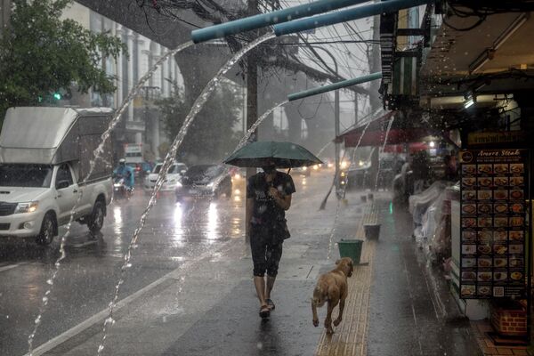 Мужчина на улице во время сильного дождя в Бангкоке (Таиланд) - Sputnik Кыргызстан