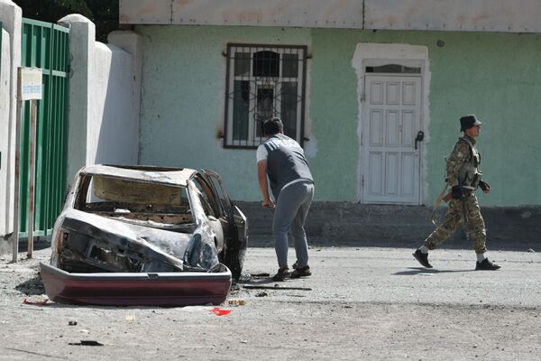 Сотрудник СМИ возле сожженного таджикскими военными автомобиля в Ак-Сае  - Sputnik Кыргызстан