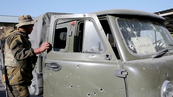 Пограничник осматривает повреждения машины  в ходе боестолкновений на кыргызско-таджикской границе - Sputnik Кыргызстан