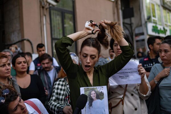 Иранка, проживающая в Турции, отрезает себе волосы во время акции протеста после смерти арестованной в Тегеране 22-летней Махсы Амини. Девушку задержали из-за неправильно надетого хиджаба, в отделении полиции у нее случился сердечный приступ. Через три дня Махса скончалась в больнице. - Sputnik Кыргызстан