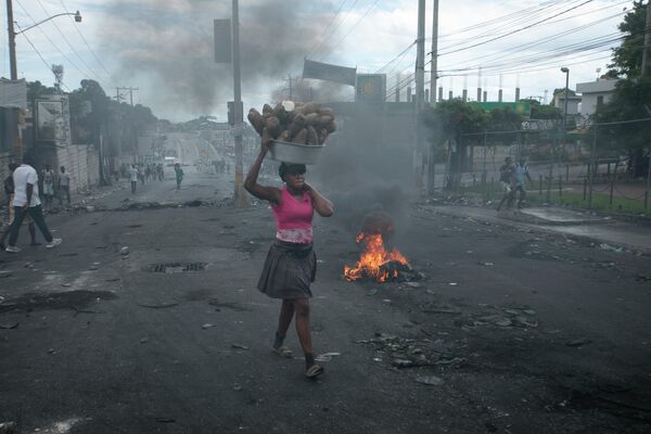 Женщина-продавец идет по улице во время митинга против повышения цен на топливо в Порт-о-Пренсе  (Гаити) - Sputnik Кыргызстан