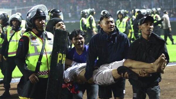 Футбольные болельщики несут раненого в результате давки после футбольного матча на стадионе Канжурухан в Маланге, Индонезия. 1 октября 2022 года - Sputnik Кыргызстан