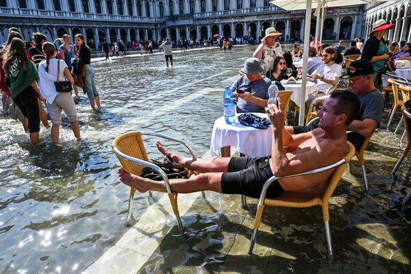 Туристы на террасе кафе на затопленной площади Сан-Марко в Венеции (Италия). Затопление стало следствием регулярного (в том числе сезонного) подъема воды. - Sputnik Кыргызстан