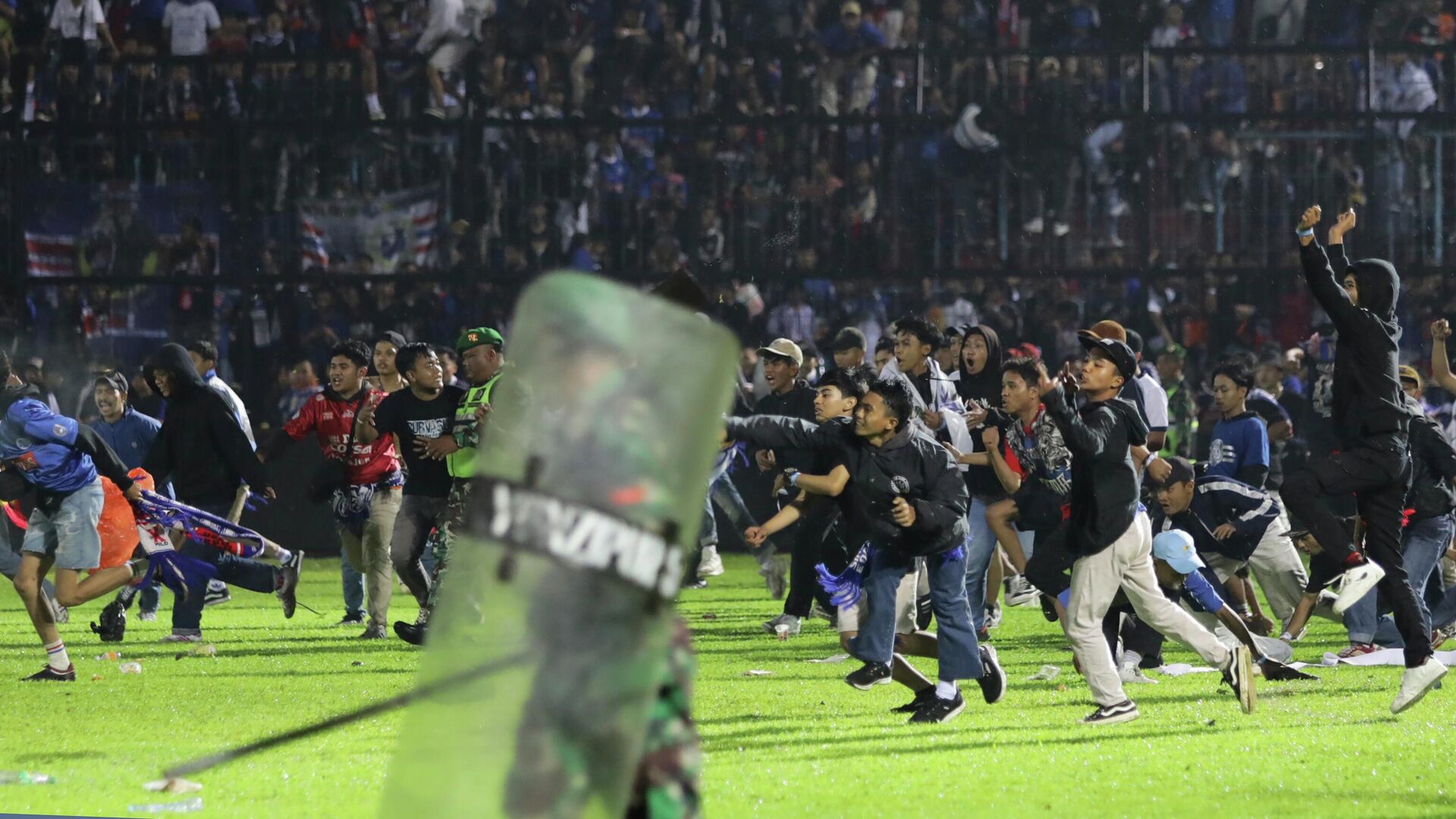 Футбольные болельщики выходят на поле во время столкновения между болельщиками на стадионе Канжурухан в Маланге, Индонезия. 1 октября 2022 года - Sputnik Кыргызстан, 1920, 02.10.2022