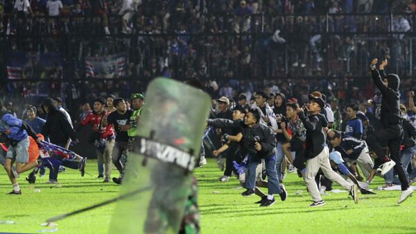 Футбольные болельщики выходят на поле во время столкновения между болельщиками на стадионе Канжурухан в Маланге, Индонезия. 1 октября 2022 года - Sputnik Кыргызстан