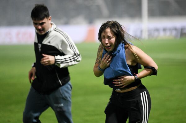 Болельщики футбольной команды Gimnasia de La Plata задыхаются от слезоточивого газа, распыленного полицией во время матча местного турнира в Ла-Плате (Аргентина) - Sputnik Кыргызстан
