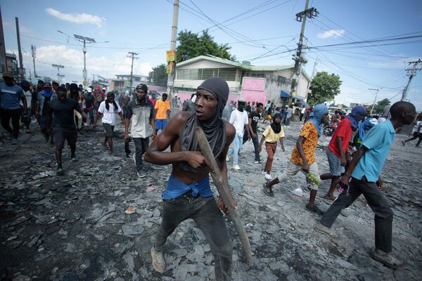 Мужчина с куском дерева, имитирующим оружие, во время акции протеста с требованием отставки премьер-министра Гаити Ариэля Генри - Sputnik Кыргызстан