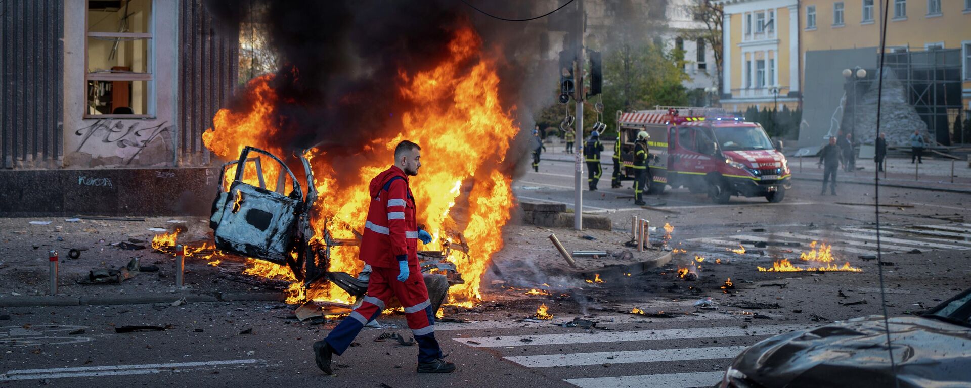 Медицинский работник идет мимо горящей машины после взрыва в Киеве, Украина - Sputnik Кыргызстан, 1920, 11.10.2022