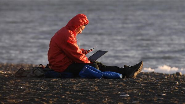 Мужчина пользуется ноутбуком и смартфоном на пляже. Архивное фото - Sputnik Кыргызстан