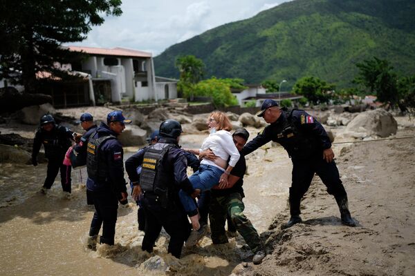 Полицейские переносят женщину через затопленную улицу в Эль-Кастано (Венесуэла). По меньшей мере три человека погибли и десятки домов повреждены в результате разлива реки Эль-Кастаньо. - Sputnik Кыргызстан