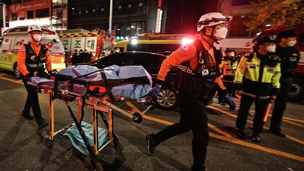 Спасатели увозят тело погибшего при давке во время празднования Хэллоуина в районе Итхэвон в Сеуле, Южная Корея. 30 октября 2022 года - Sputnik Кыргызстан