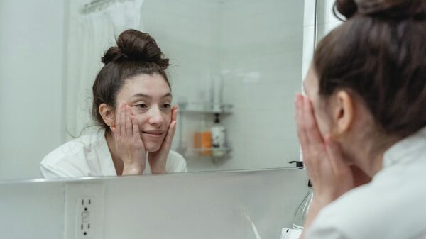 Девушка смотрится в зеркало в ванной. Иллюстративное фото - Sputnik Кыргызстан