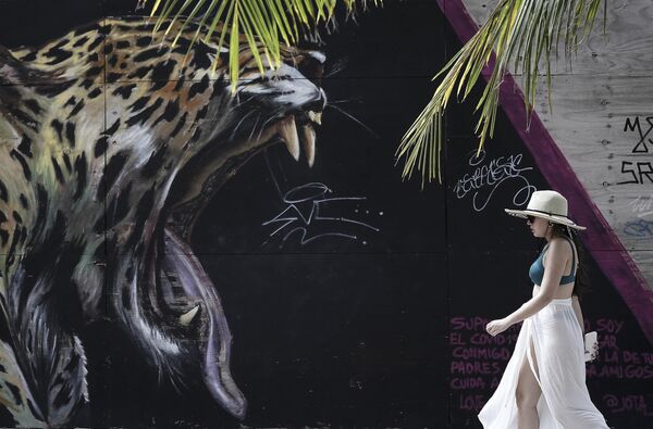 Туристка идет мимо фрески с изображением ягуара на острове Сан-Андрес, Колумбия - Sputnik Кыргызстан